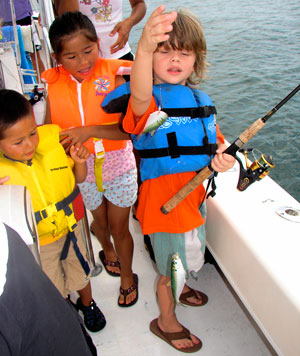 A group of kids enjoying their fishing trip out on the water.